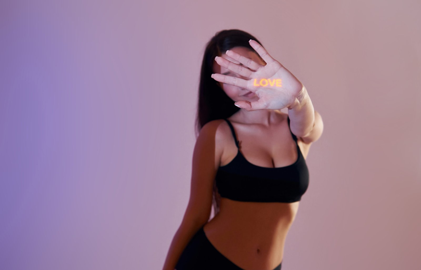 Love letter is on the palm of a hand. Beautiful young woman is in projector neon lights in the studio.